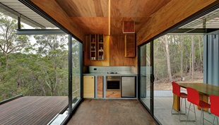 The kitchen cabinets are made of the same warm coloured ply that was used to line the containers